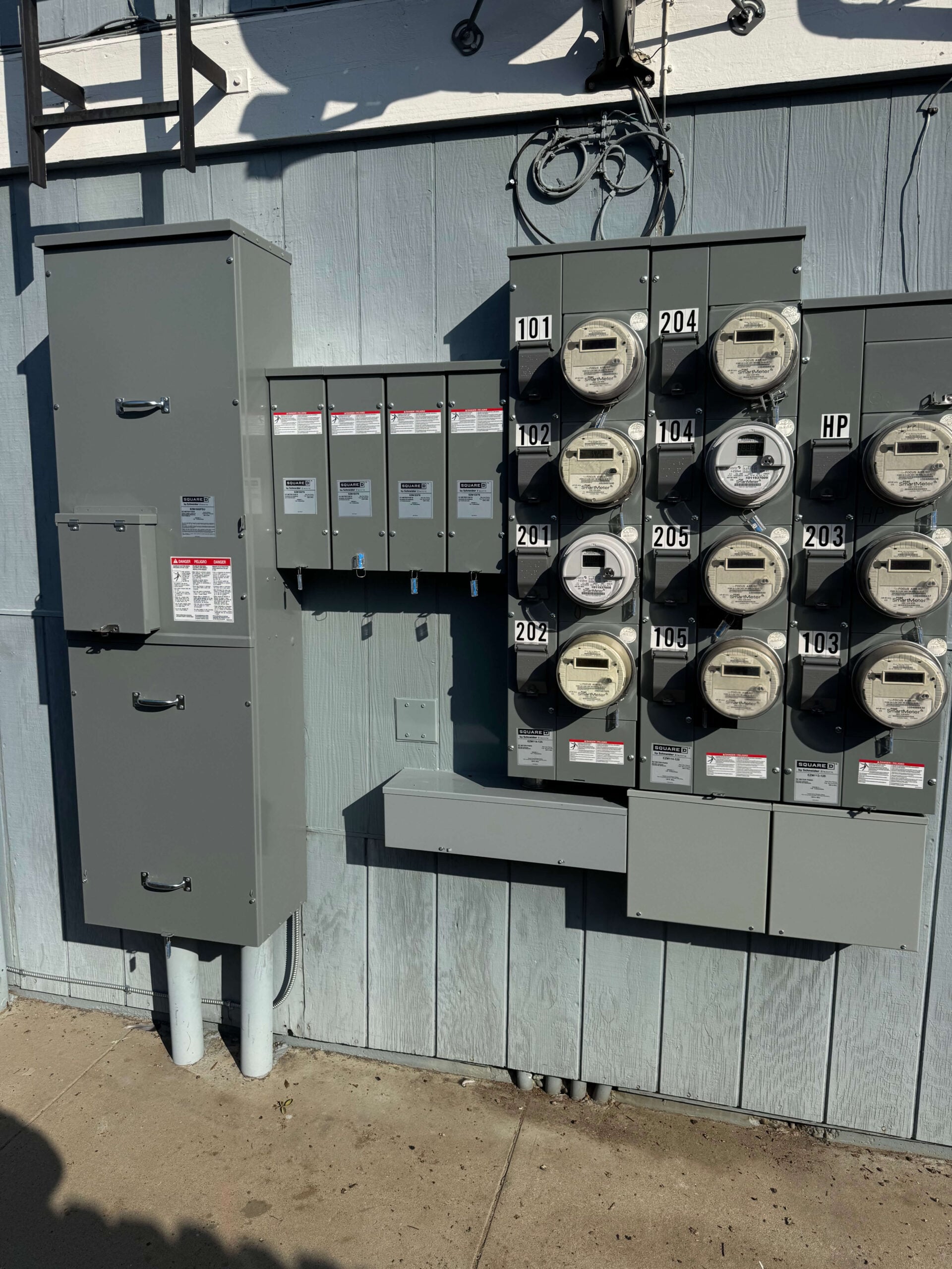 Multi-tenant electric meter stack and Square D main service panel installation on an exterior building wall.