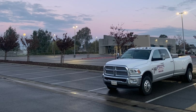 White Advanced Electric dual-rear-wheel commercial service truck parked in a commercial lot at dawn.